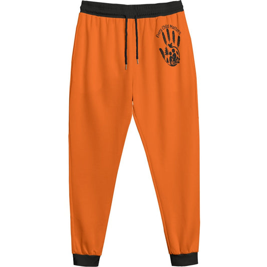 Bright orange sweatpants with black elastic waistband, drawstring, and ribbed ankle cuffs, featuring a black graphic print on the upper left thigh.