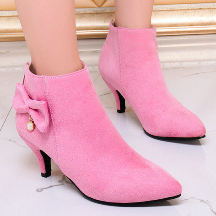 Pink ankle boots with a bow detail on a light background