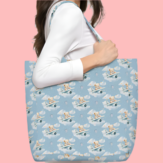 Tote bag with teddy bear pattern held by a person against a pink background