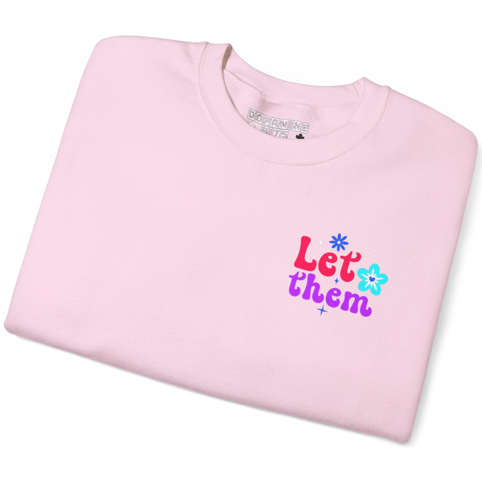 Folded pink t-shirt with colorful text and flower graphics on a white background