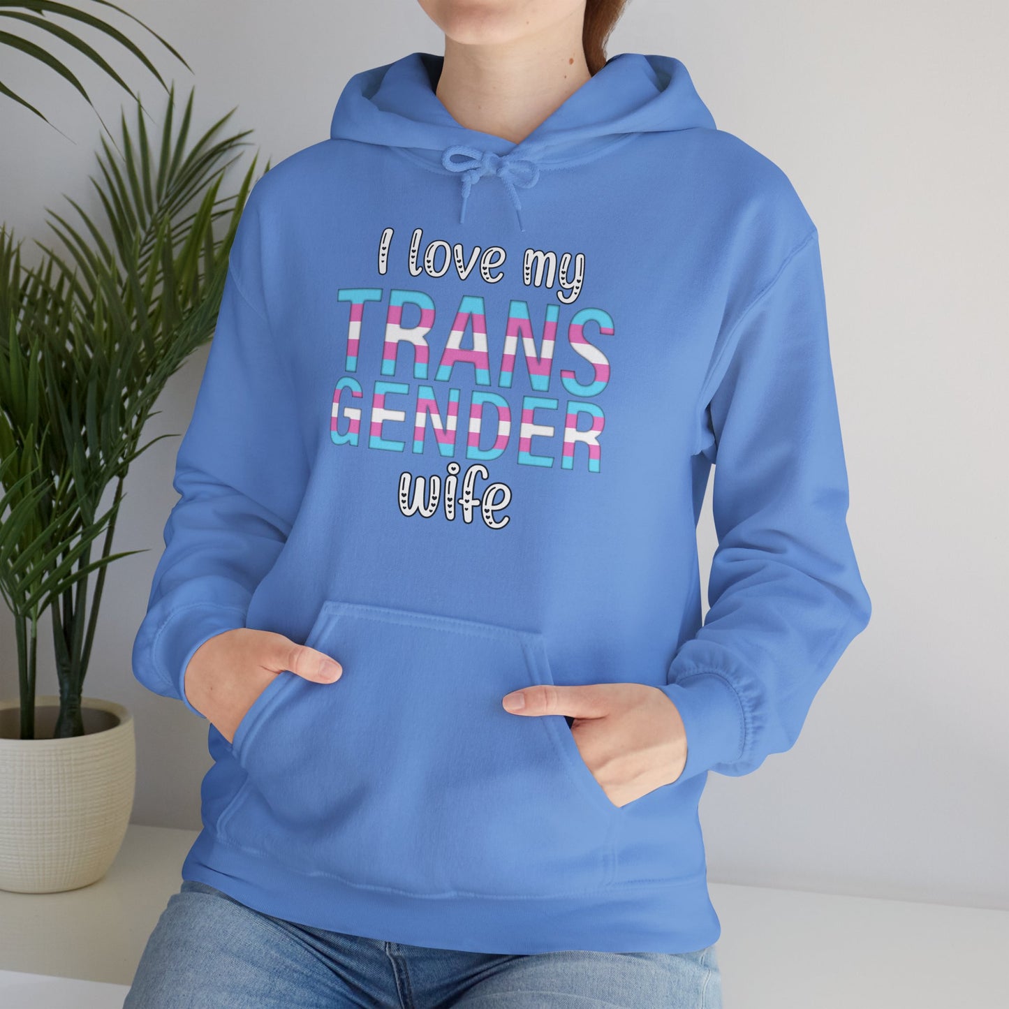 Person wearing a blue hoodie with text 'I love my TRANS GENDER wife' against a neutral background.