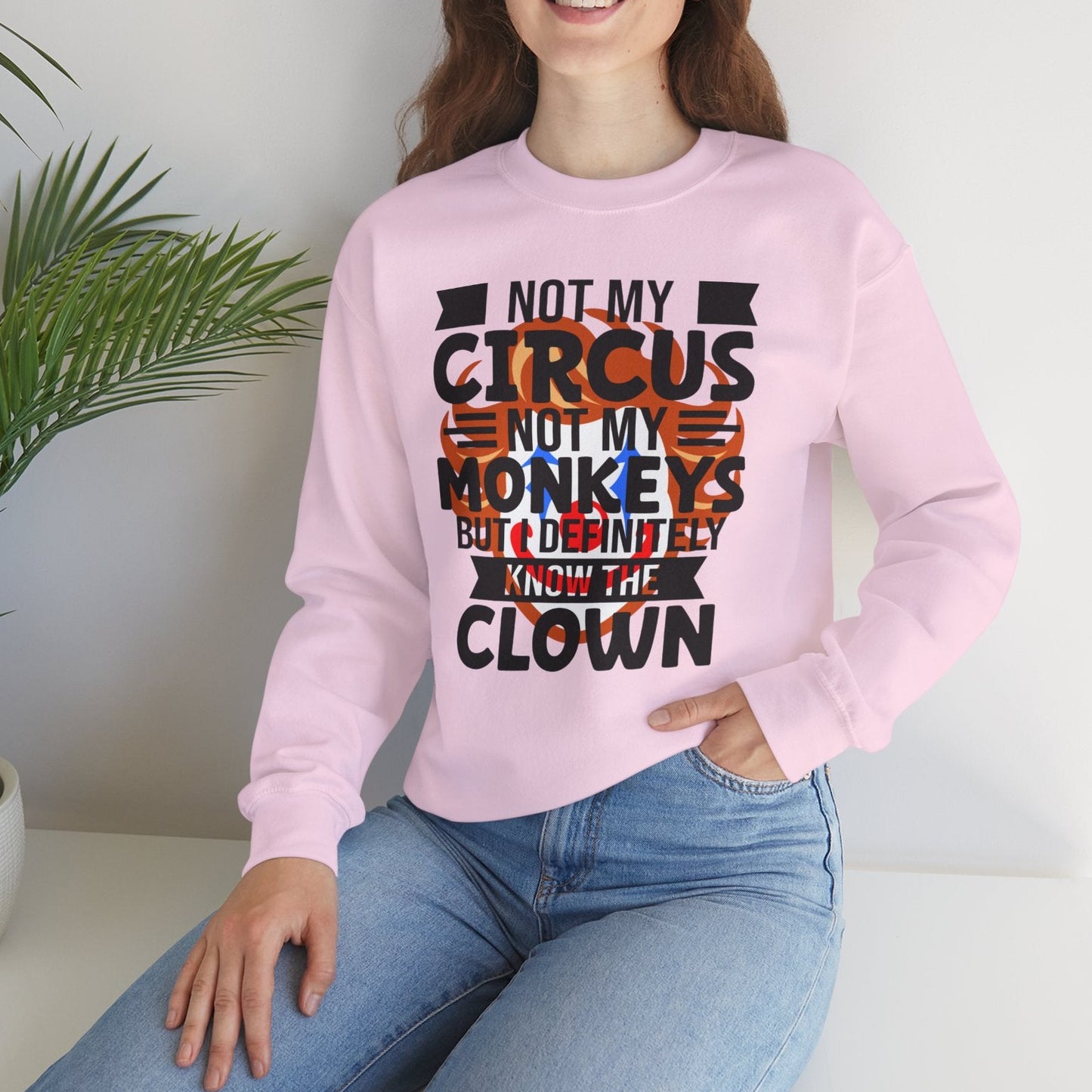 Person wearing a pink sweatshirt with text, sitting on a white surface with a plant in the background