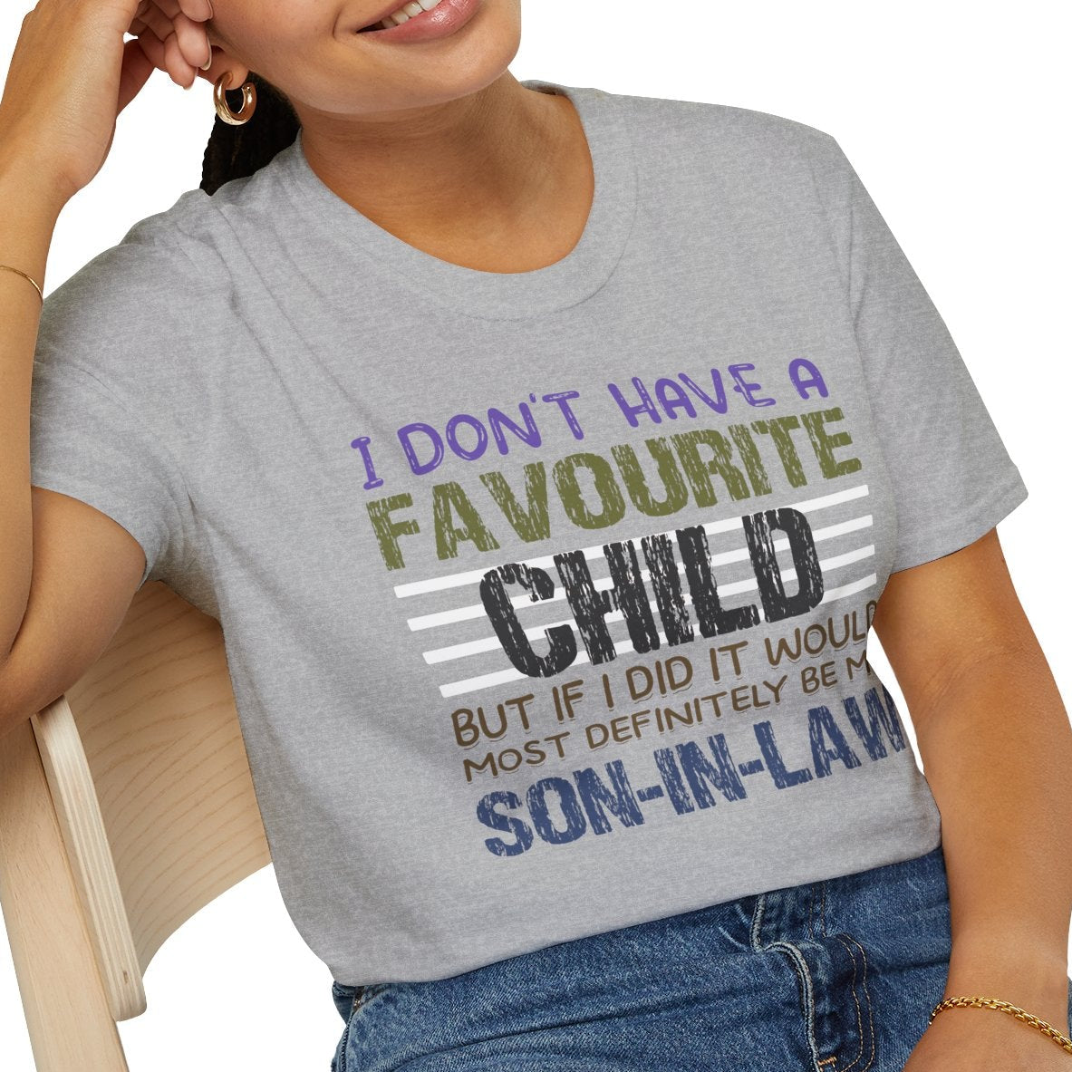 Woman wearing a gray t-shirt with humorous text design, sitting on a chair.