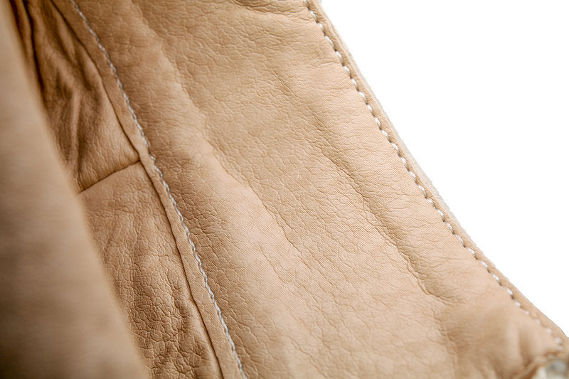 Close-up of beige leather texture with stitching detail