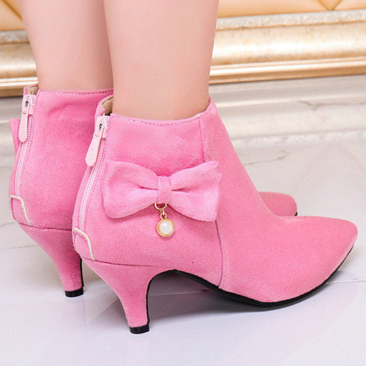 Pink low-heeled boots with a bow detail on a light background