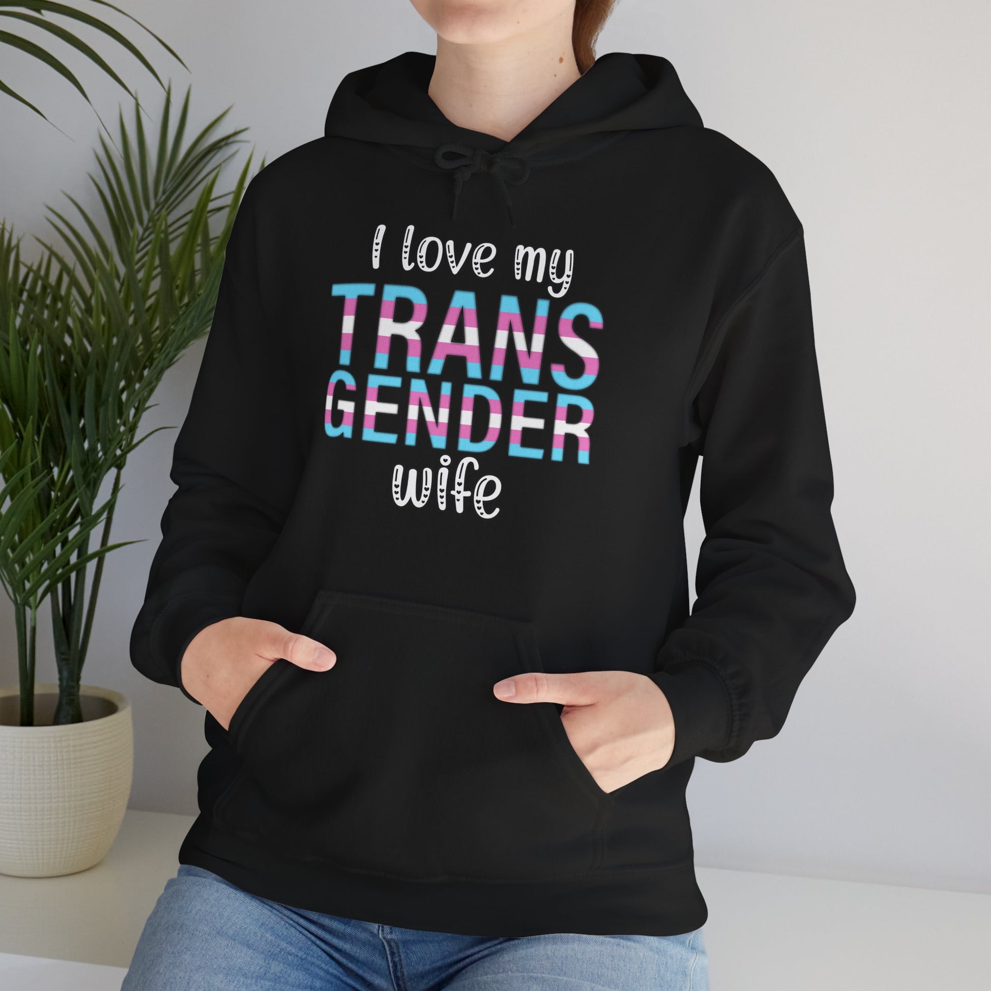 Person wearing a black hoodie with 'I love my TRANS GENDER wife' text.