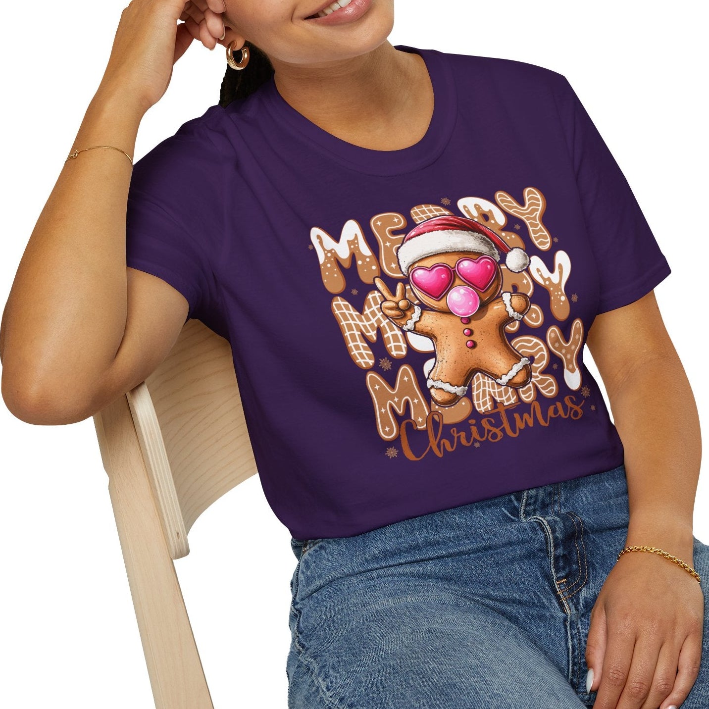 Person wearing a purple t-shirt with a Christmas design, sitting on a chair.