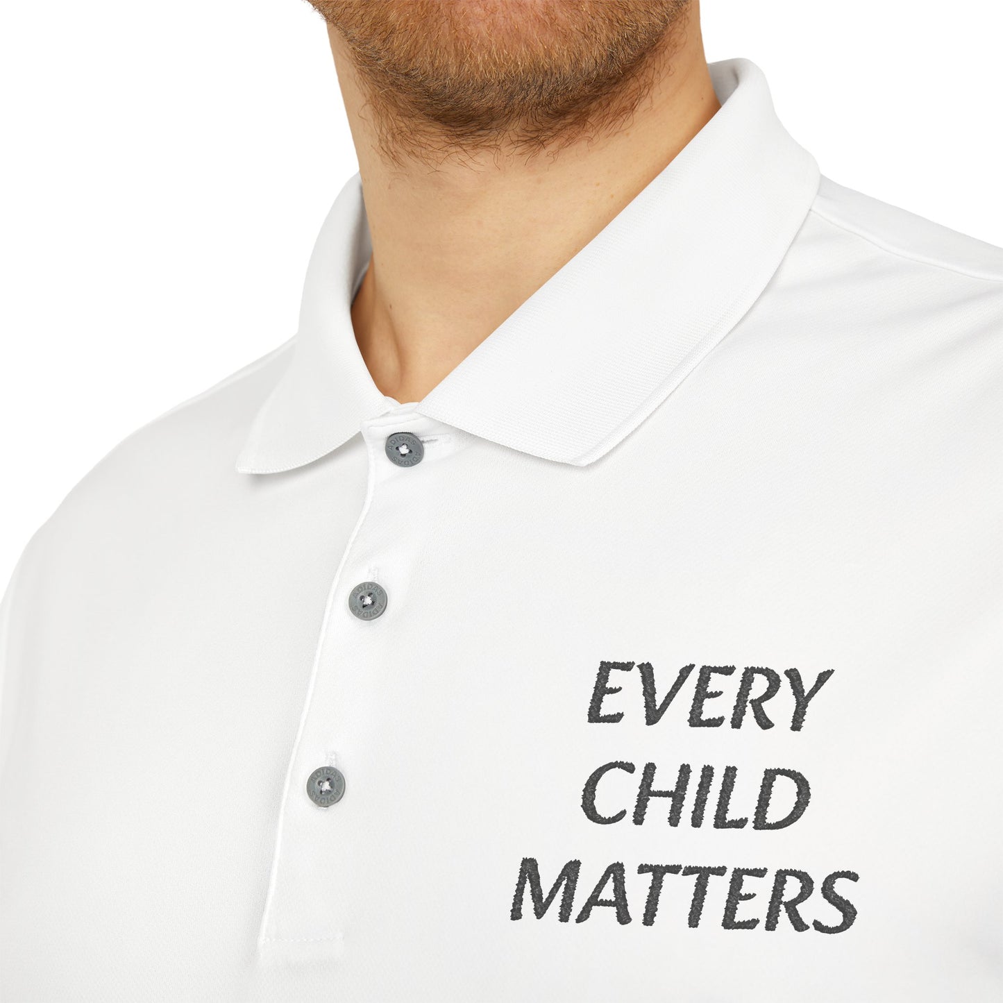Close-up of a white polo shirt worn by a model, featuring the text 'EVERY CHILD MATTERS' embroidered in black on the left chest.
