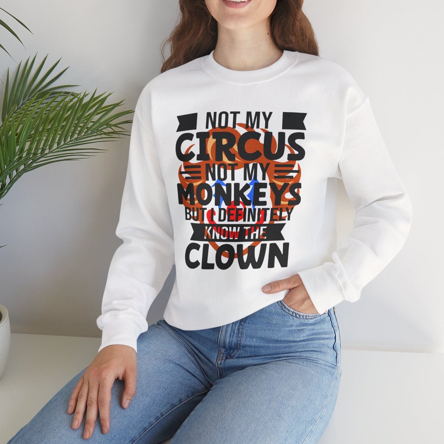 Woman wearing a white sweatshirt with a humorous text design, sitting in a room with a plant.