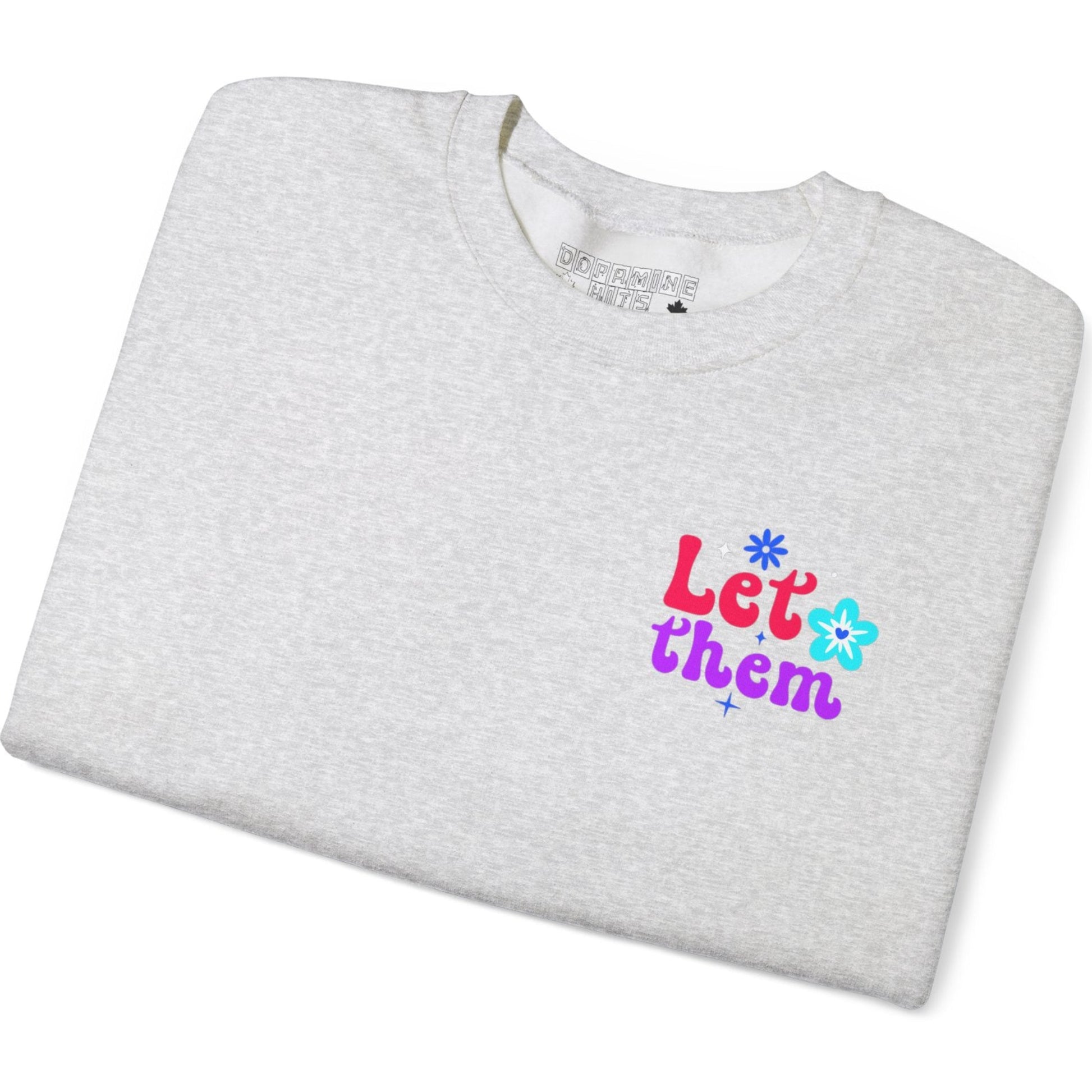 Folded ash gray t-shirt with colorful text and flower graphics on a white background