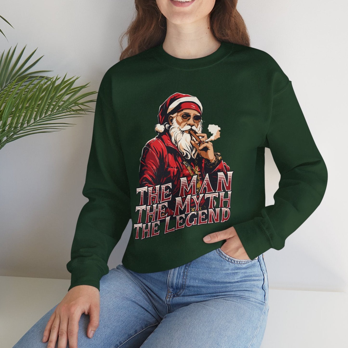 Person wearing a green sweatshirt with a graphic and text, sitting in a room with a plant.