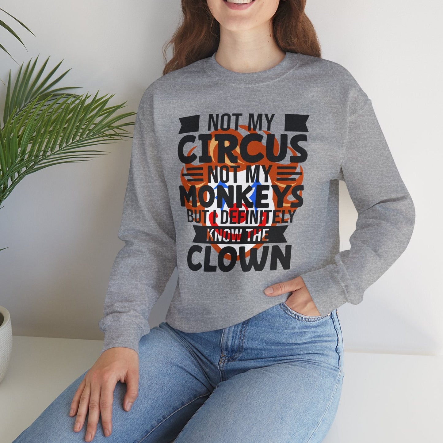 Woman wearing a gray sweatshirt with a humorous quote, sitting in a room with a plant.