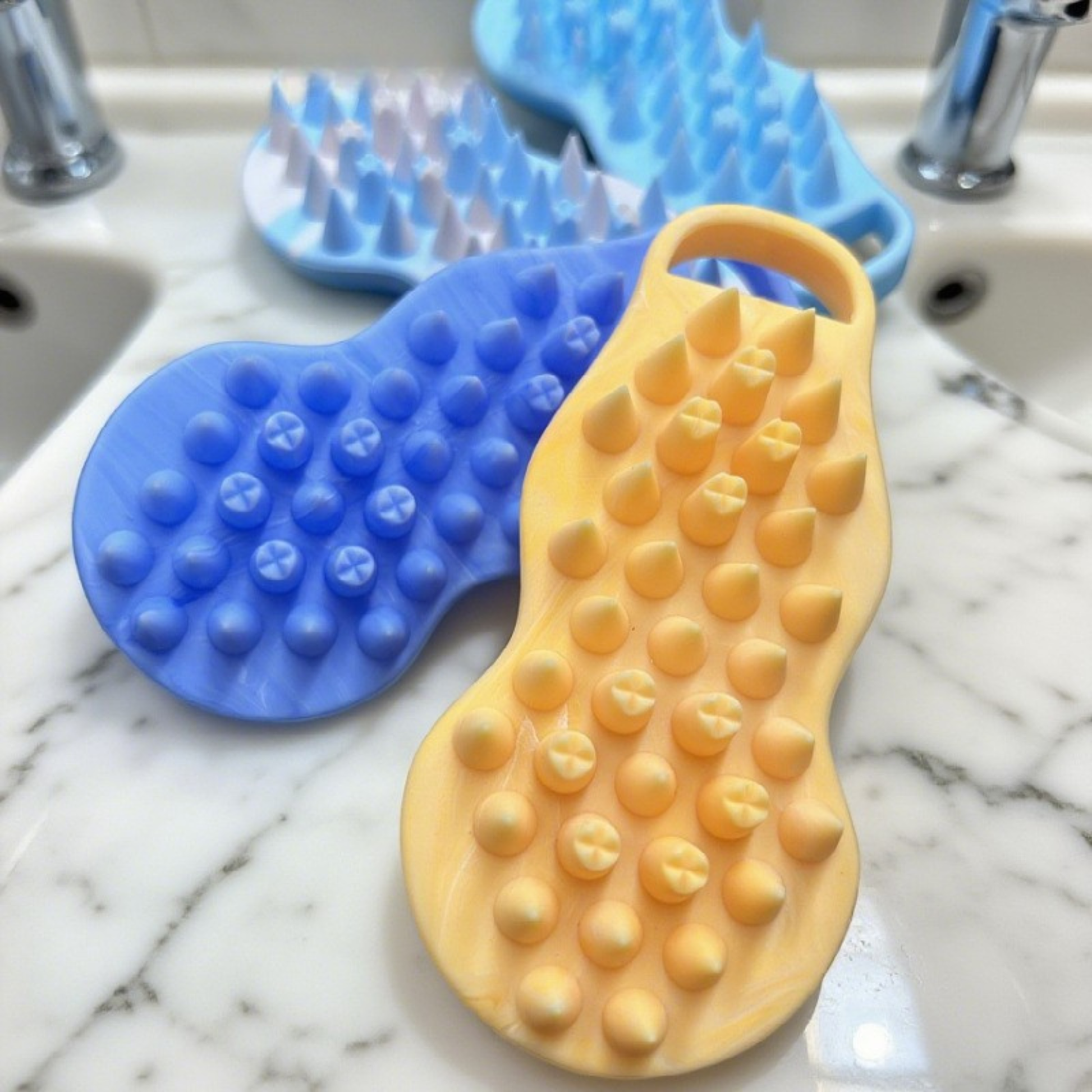 Yellow and blue silicone scrubbers on a marble countertop.