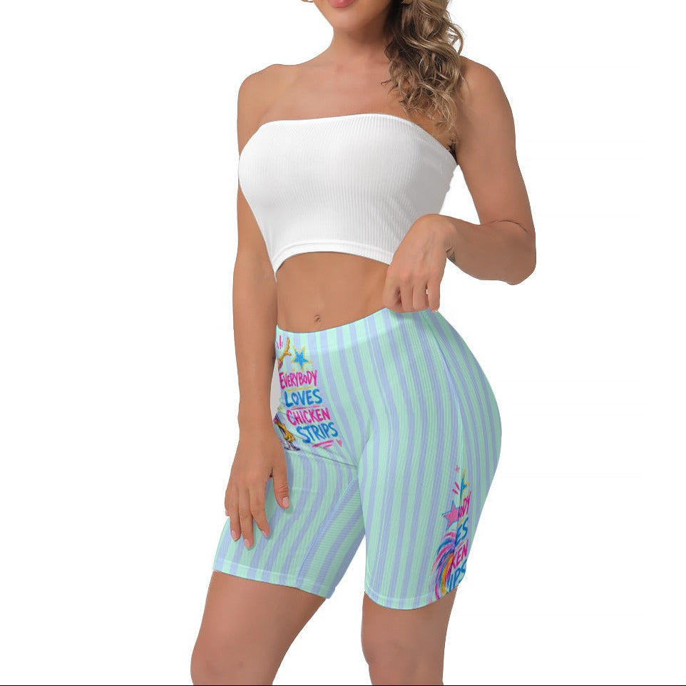 A woman modeling a white strapless crop top and light blue and seafoam striped biker shorts with colourful text and graphics, set against a plain white background.