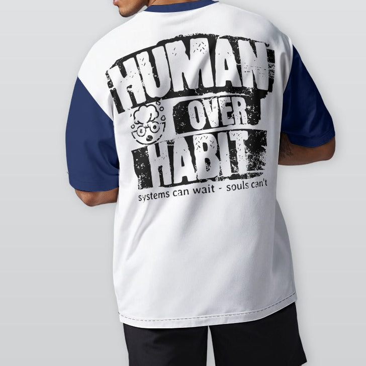 Person wearing a white and blue t-shirt with 'Human Over Habit' text on the back, standing against a plain background.