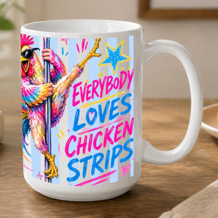 A white ceramic coffee mug with a funny colourful graphic of a pole dancing chicken and the text 'EVERYBODY LOVES CHICKEN STRIPS' in pink and blue lettering, set on a wooden table in a cozy room.
