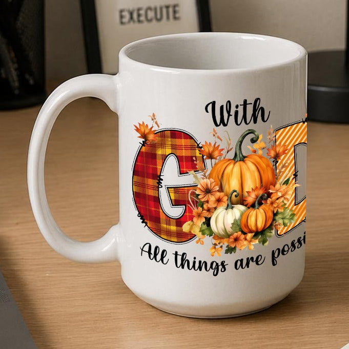A white ceramic coffee mug with a fall harvest design sits on a wooden desk next to an open laptop, notebook, and framed motivational print.