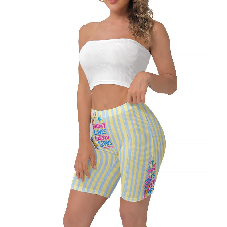 A woman modeling a white strapless crop top and pastel yellow-and-blue striped biker shorts with colourful text and graphics on the legs, against a plain white background.