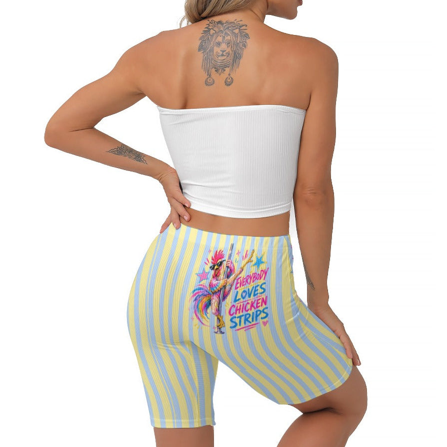 A woman shown from the back wearing light blue and yellow vertically striped biker shorts with a colourful graphic print on the back, paired with a white strapless crop top, against a plain white background.