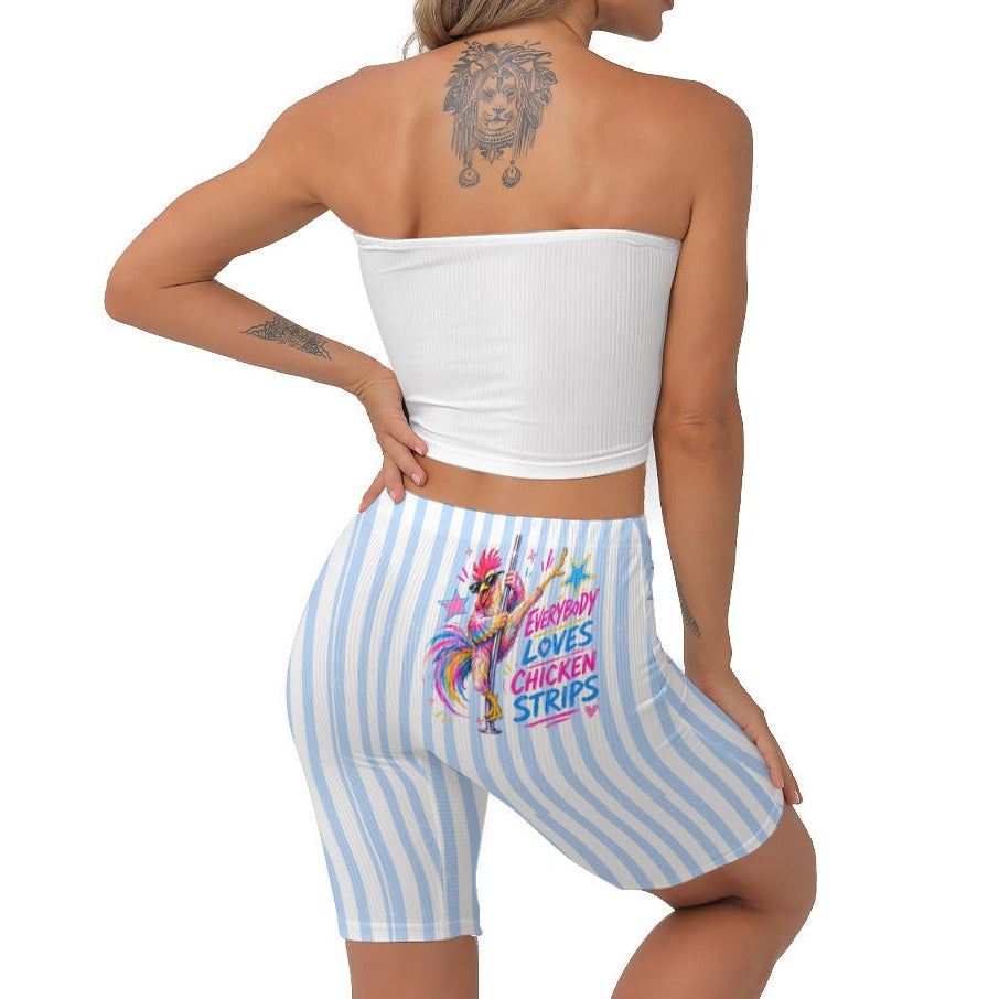 A woman shown from the back wearing a white strapless crop top and light blue and white striped biker shorts with a colourful graphic on the back. The background is solid white.