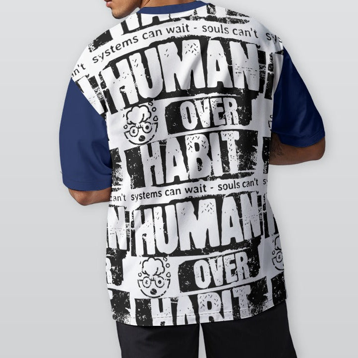Person wearing a shirt with 'Human Over Habit' text on the back, standing against a plain background