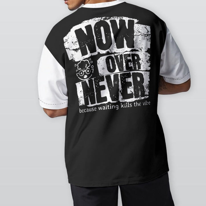 Person wearing a black and white t-shirt with text on the back, standing against a plain background