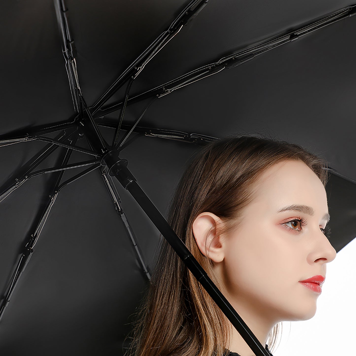 Woman holding an umbrella with a black interior on a neutral background