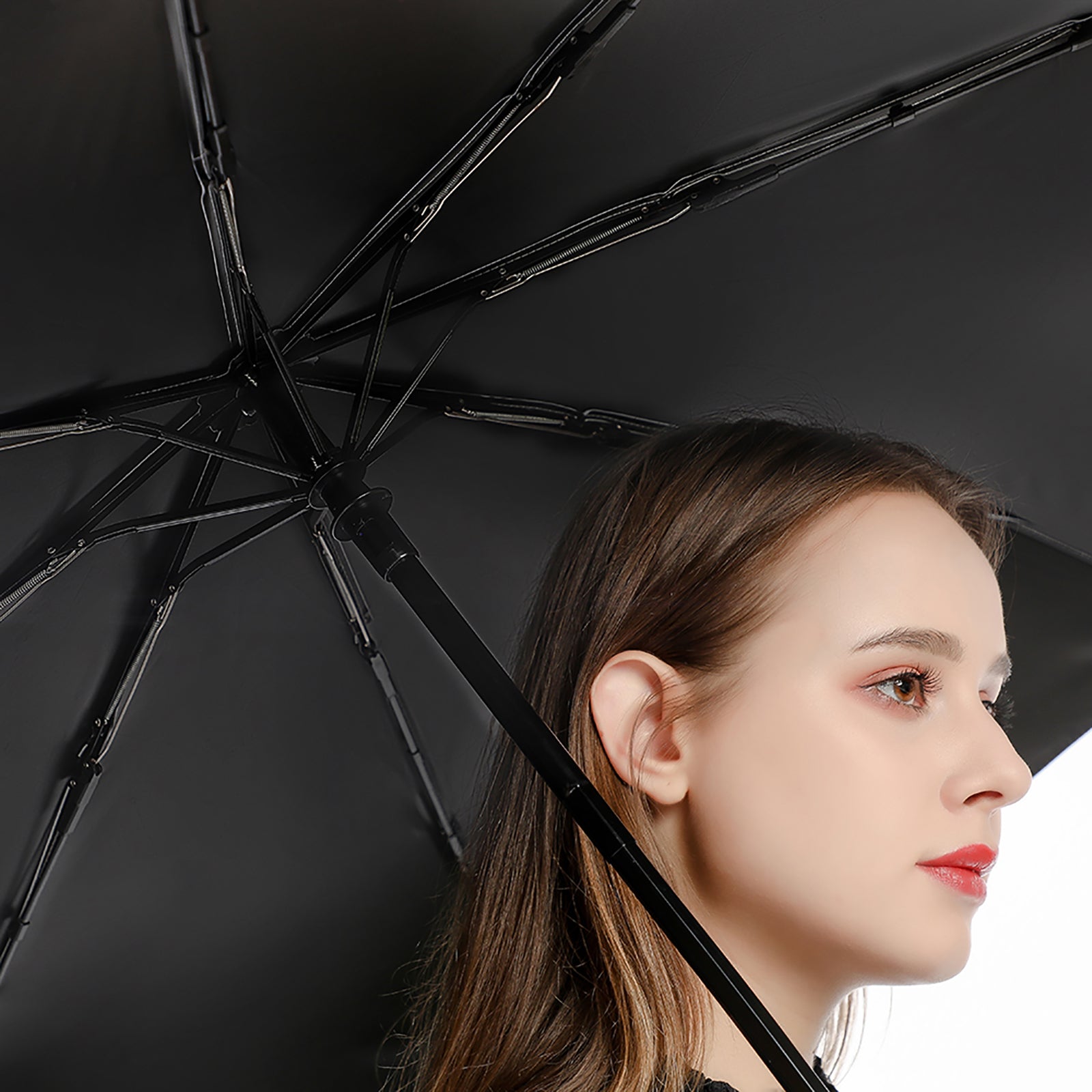 Woman holding an umbrella with a black interior on a neutral background
