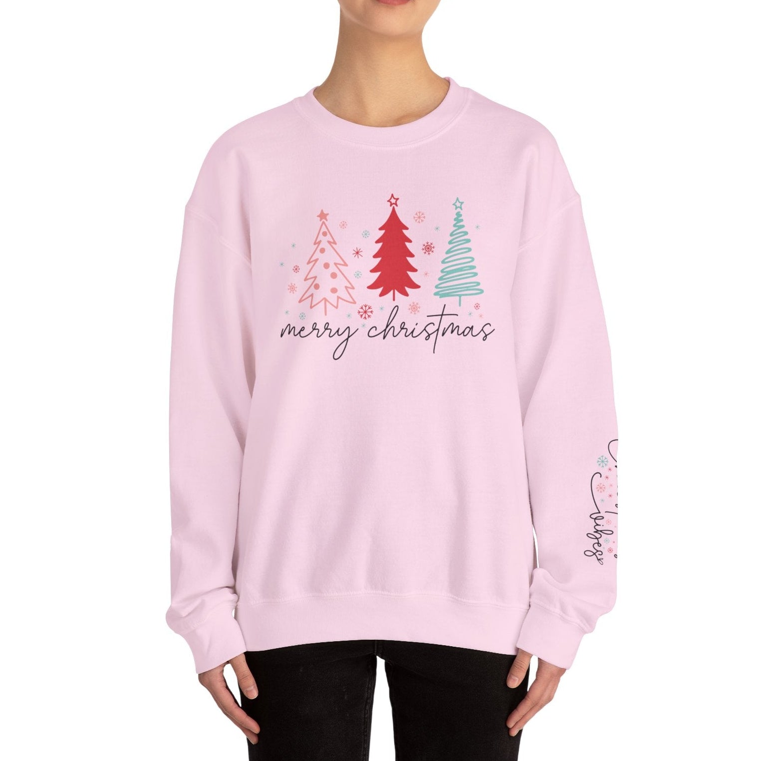 Person wearing a pink 'Merry Christmas' sweater with Christmas tree design on a white background
