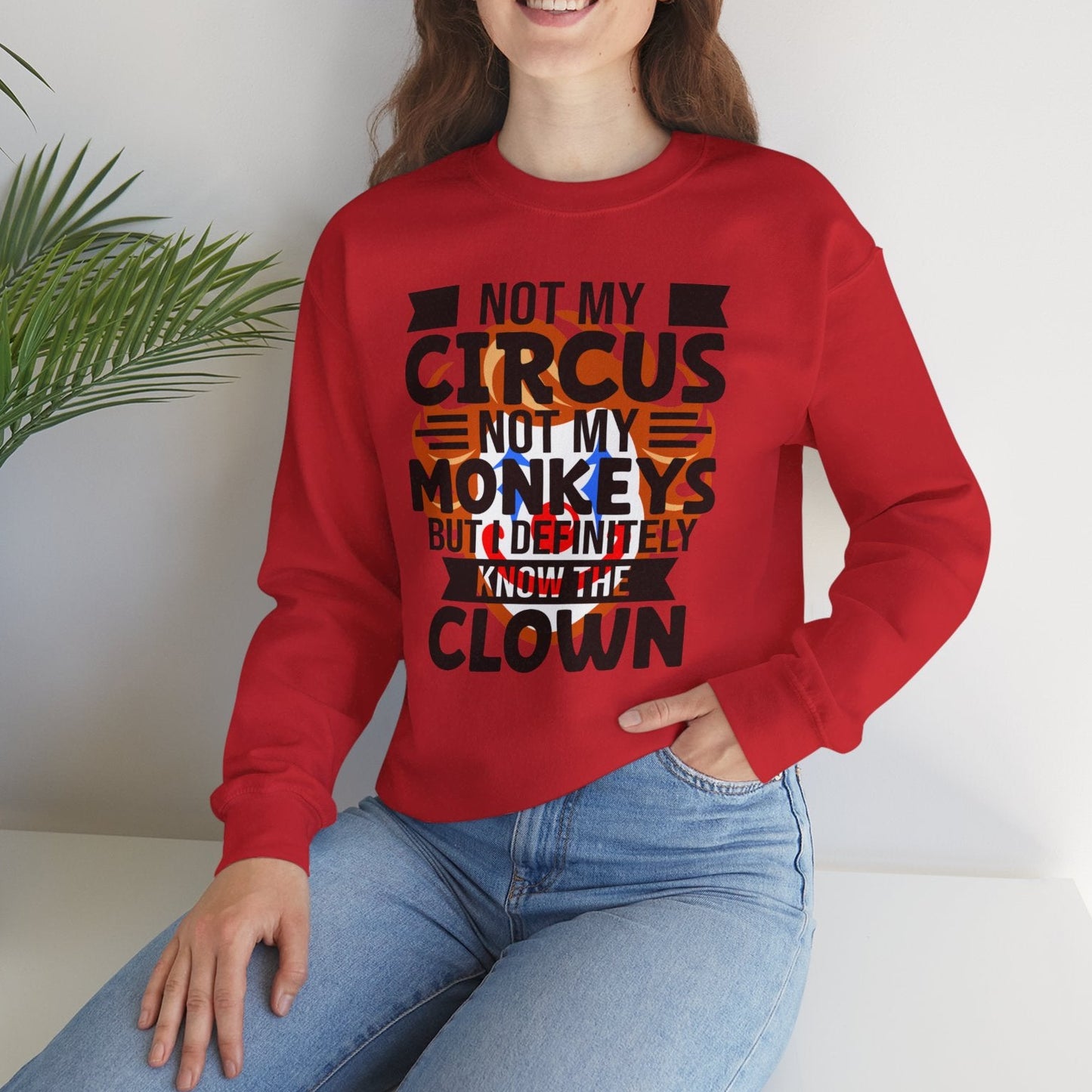 Person wearing a red sweatshirt with text, sitting on a white surface with a plant in the background.