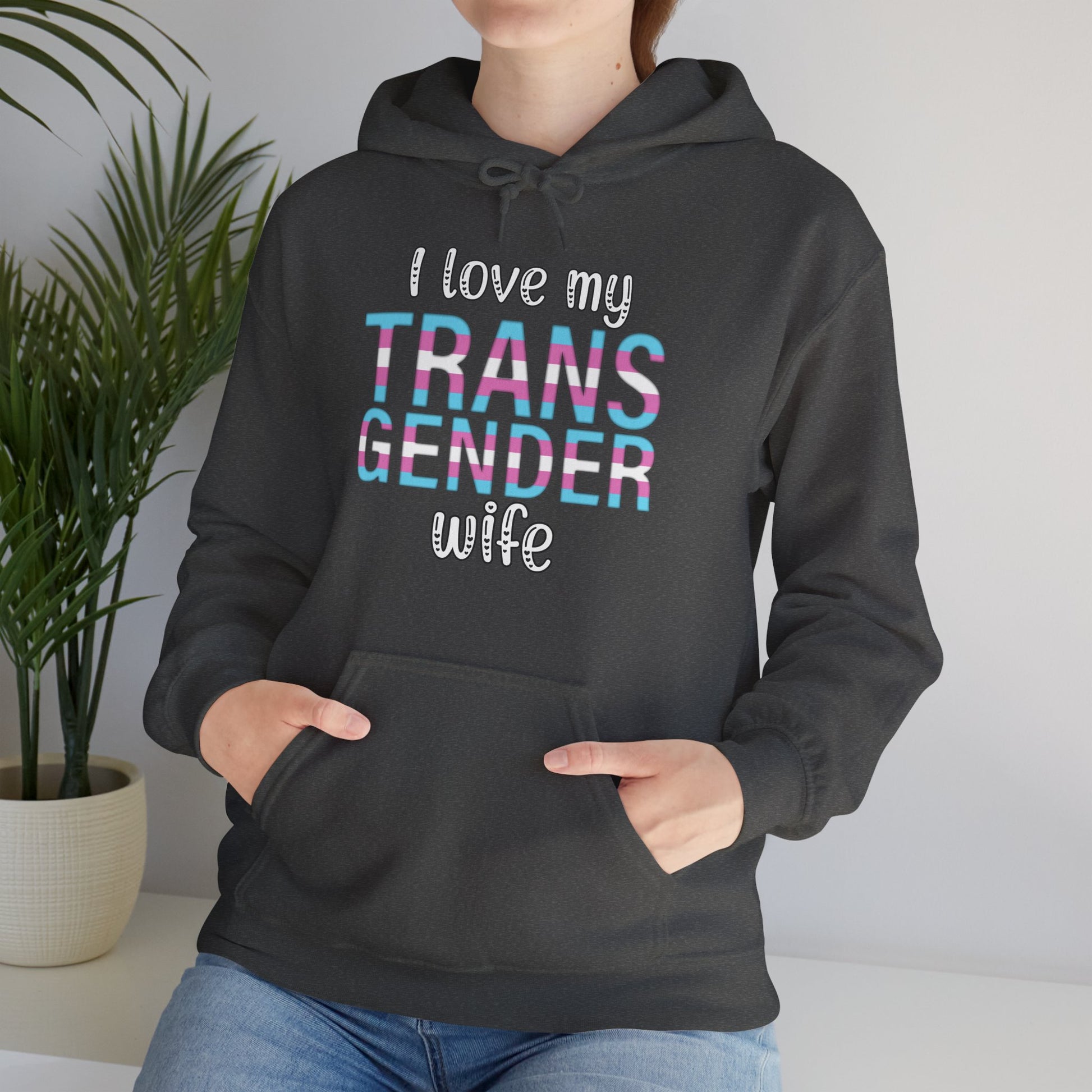 Person wearing a Heather Gray hoodie with 'I love my TRANS GENDER wife' text in colorful letters.