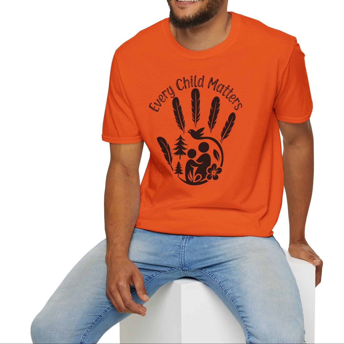 Man wearing an orange t-shirt with a graphic design and text, sitting on a white stool against a white background.