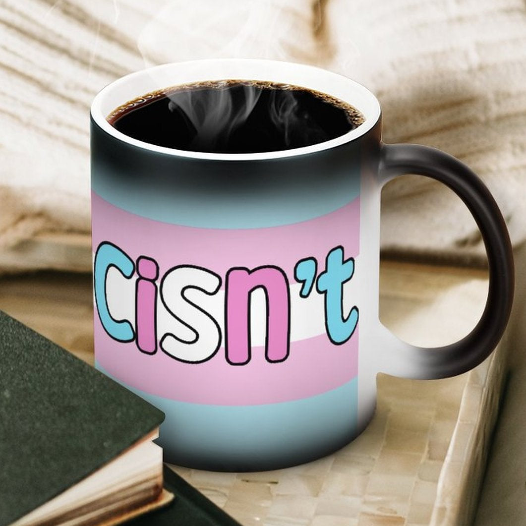 Coffee mug with 'cisn't' text on a table with books and a blanket.