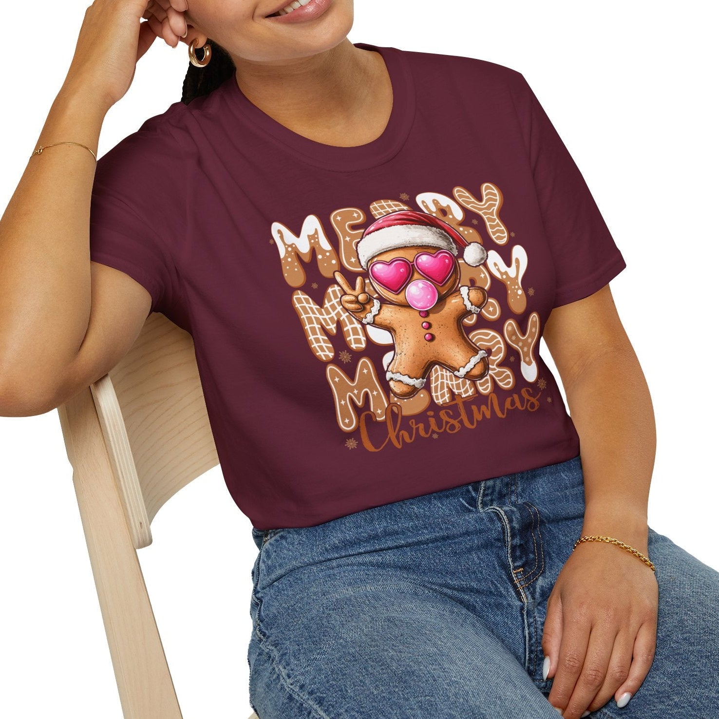 Woman wearing a maroon t-shirt with Christmas-themed design sitting on a chair.