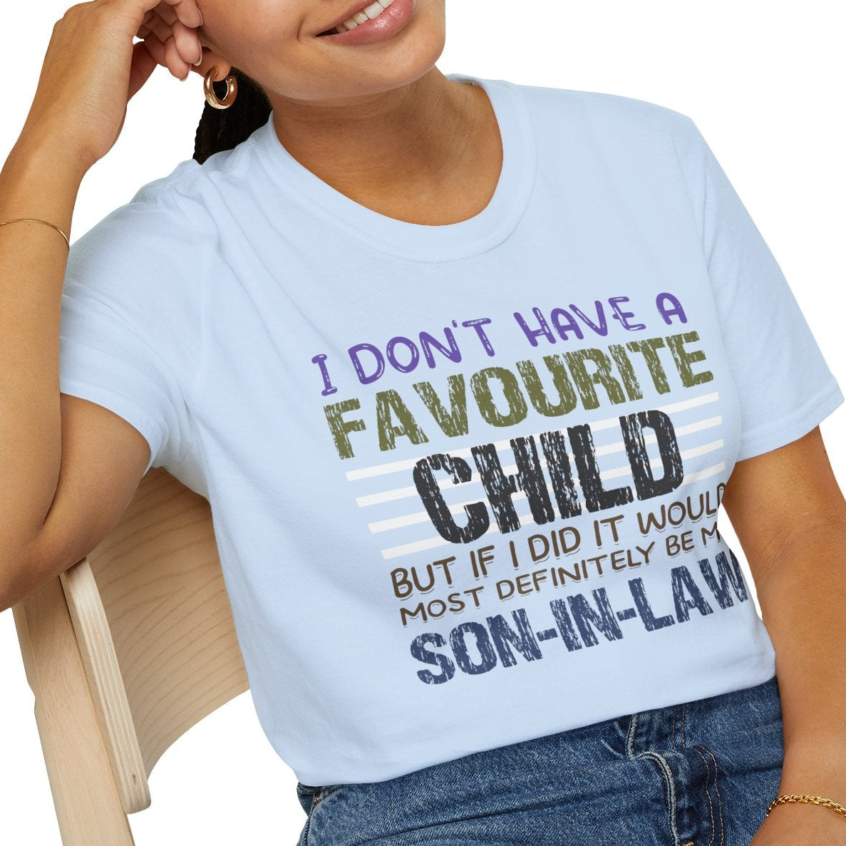 Person wearing a light blue t-shirt with humorous text design, sitting on a chair.