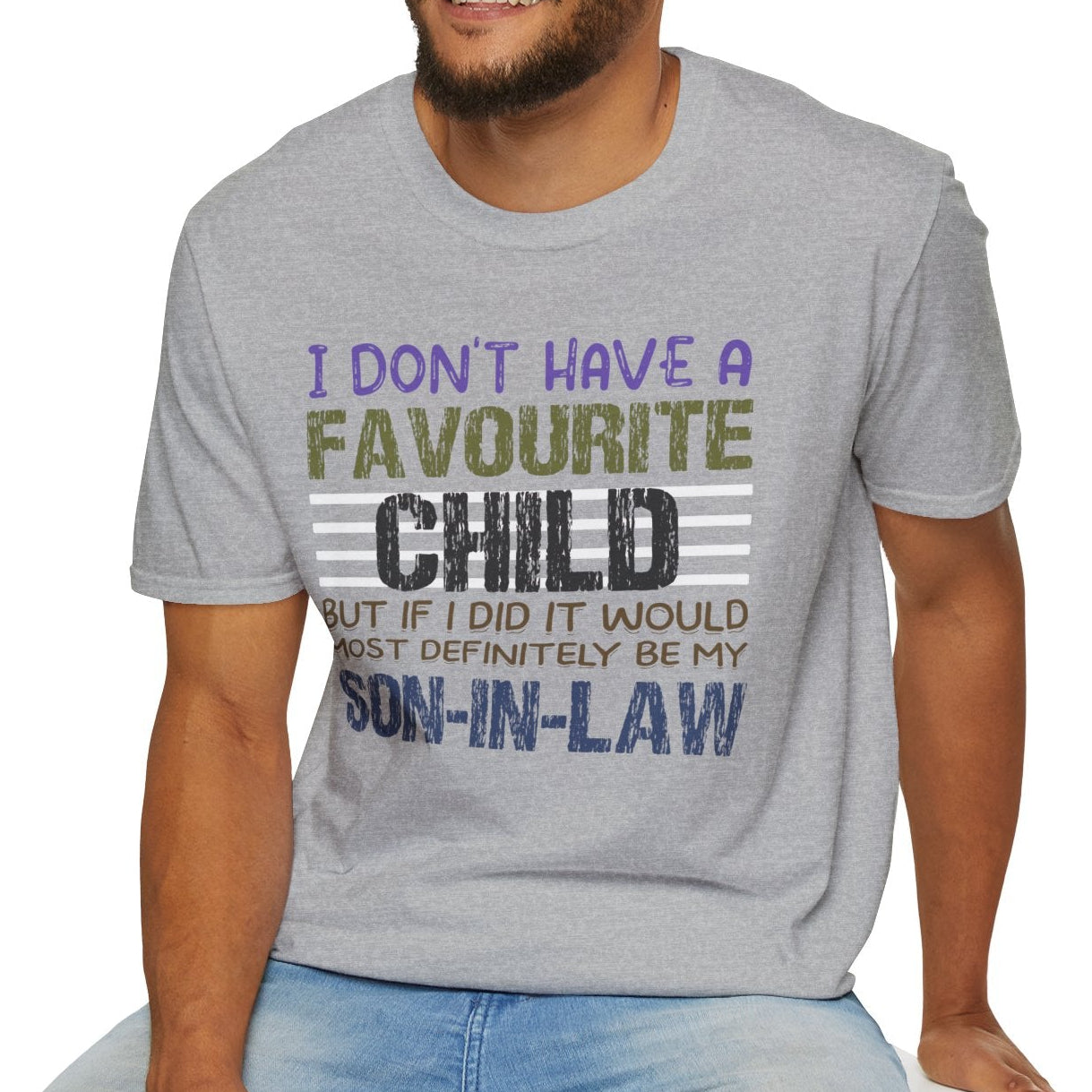 Man wearing a gray t-shirt with a graphic design and text, sitting on a white stool against a white background.