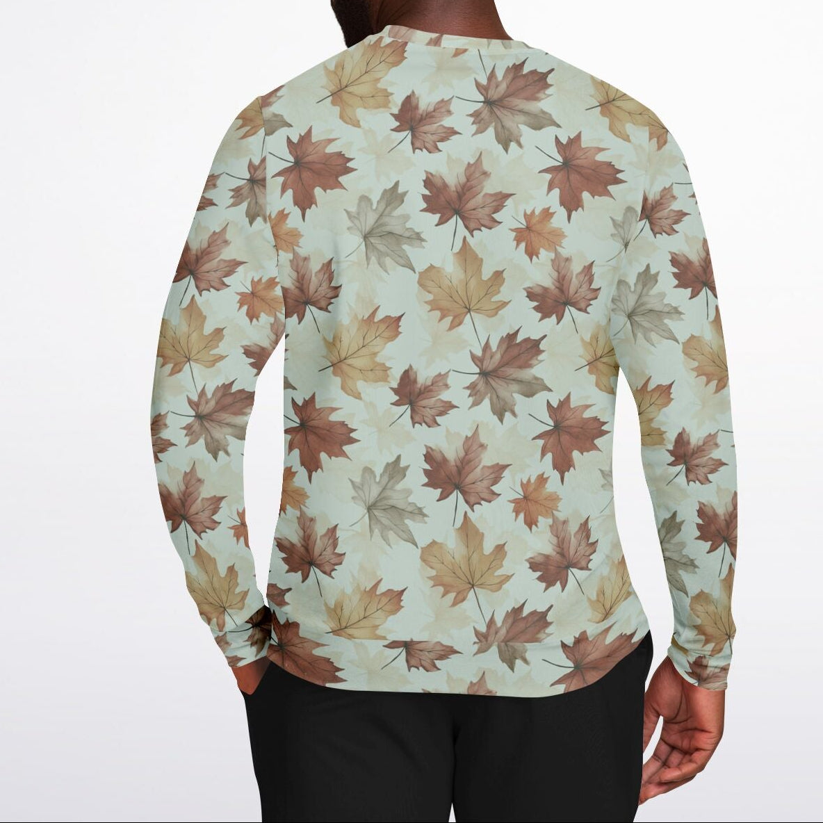 Person wearing a long-sleeve shirt with autumn leaf pattern on a plain background