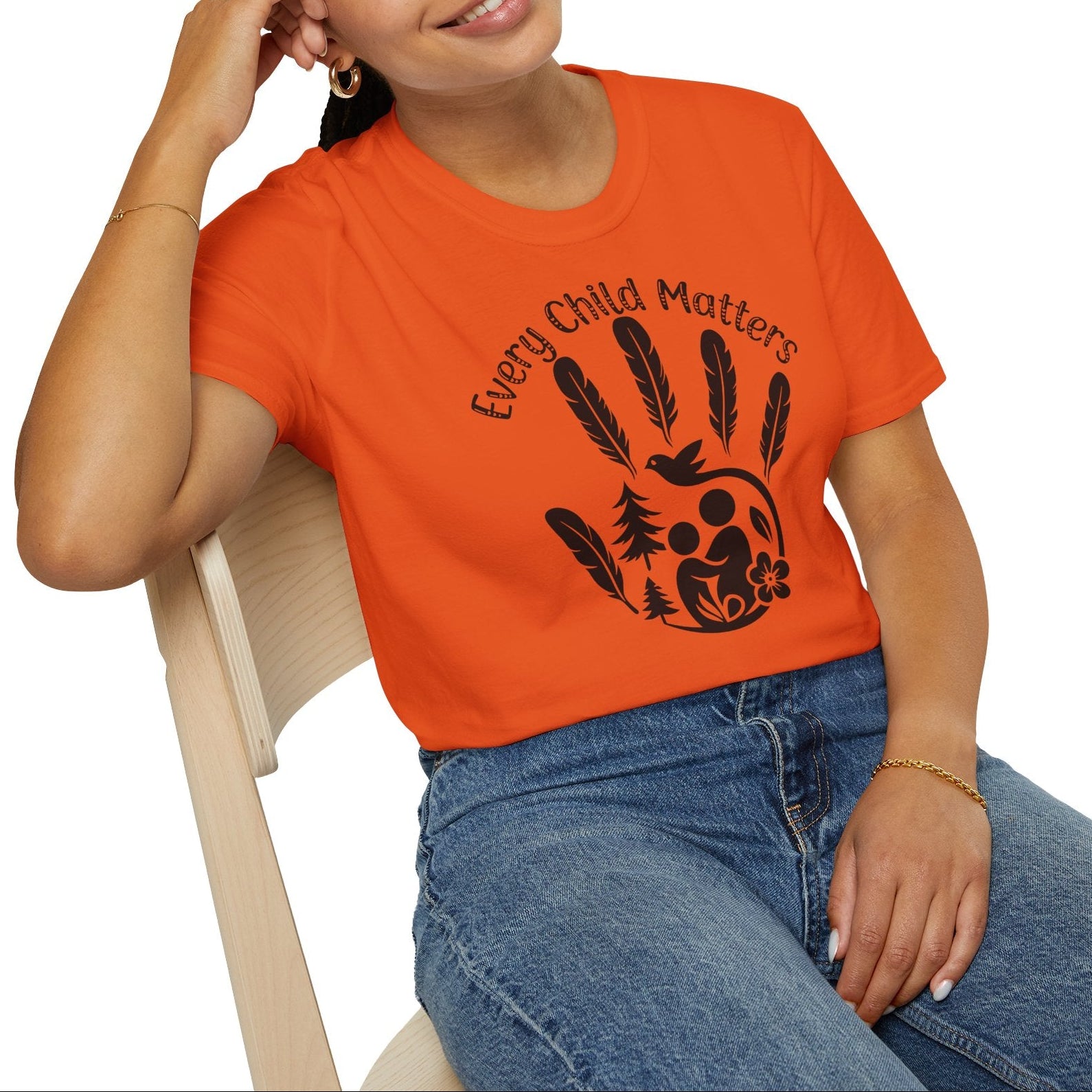 Person wearing an orange shirt with 'Every Child Matters' design, sitting on a white background