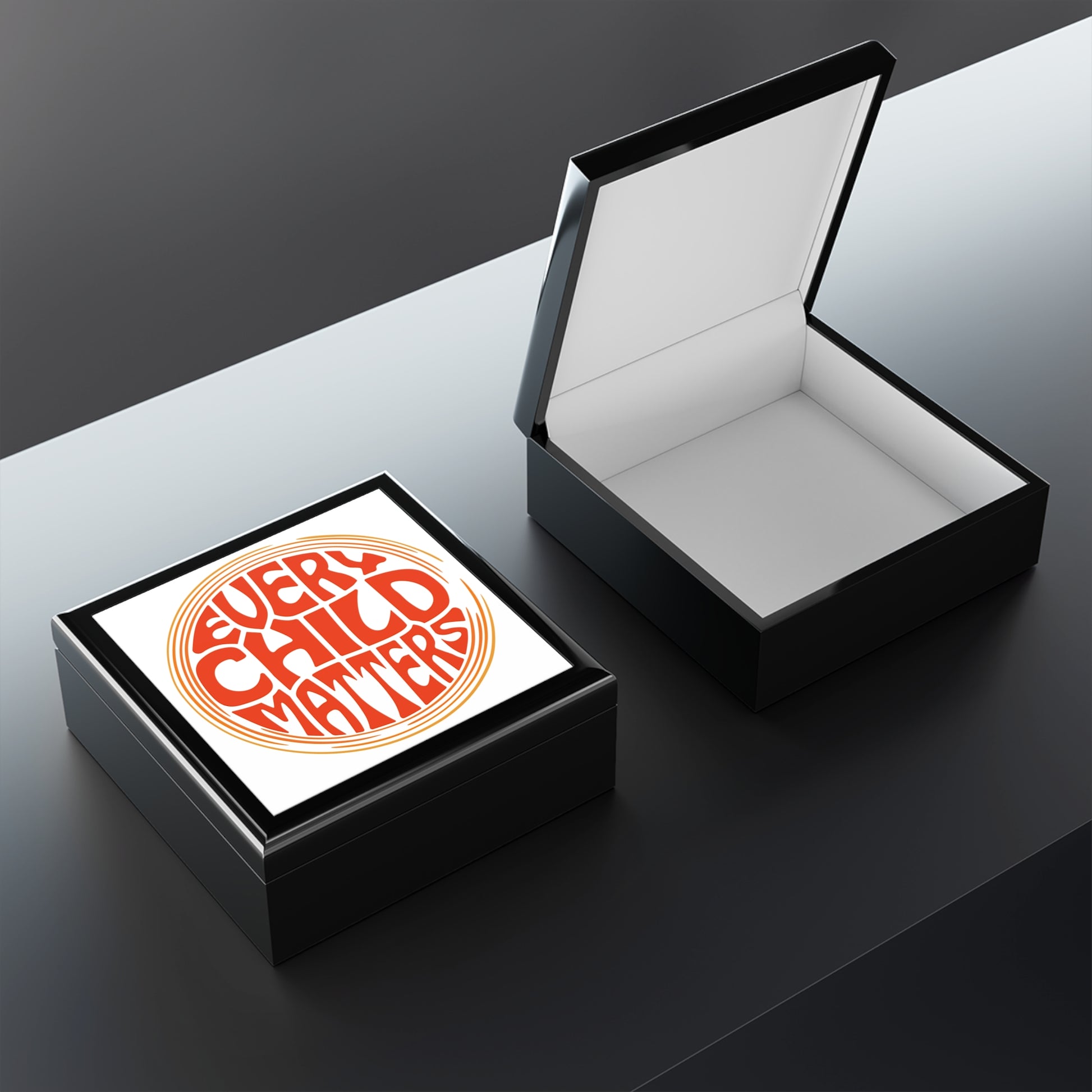 Open black jewelry box with a inside top displays 'Every Child Matters' text.