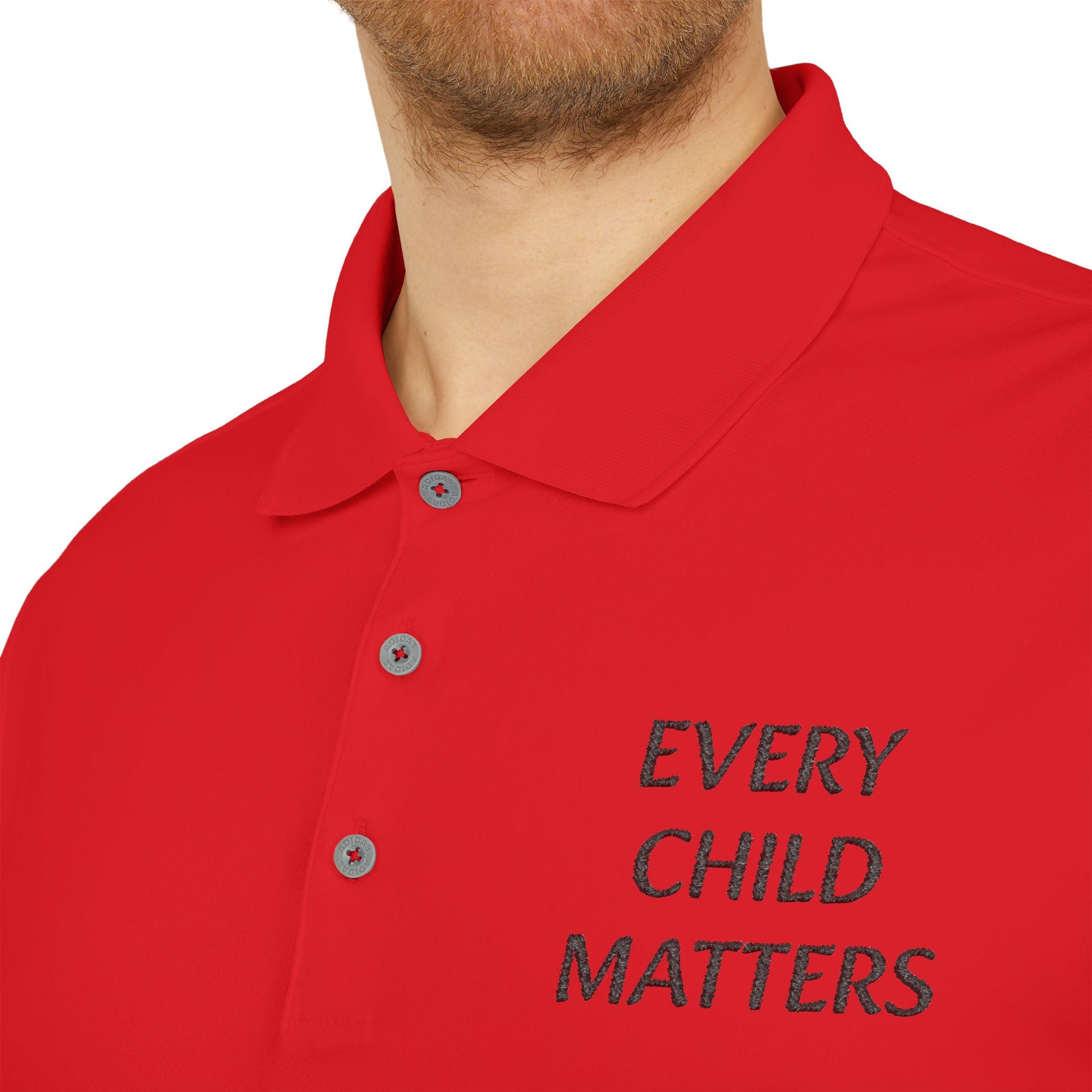 A close-up of a red polo shirt worn by a man, featuring the embroidered text 'EVERY CHILD MATTERS' in black on the left chest.
