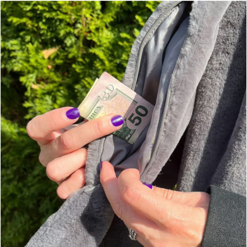 Person holding a fifty-dollar bill next to an open gray scarf secret pocket outdoors.