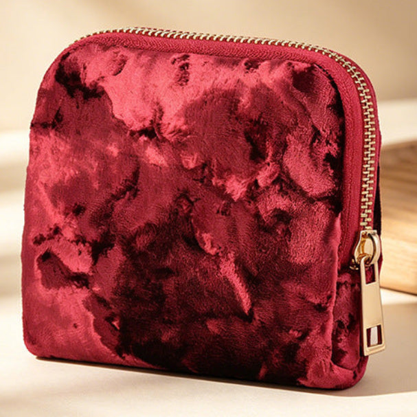 Red velvet pouch with a gold zipper on a beige background