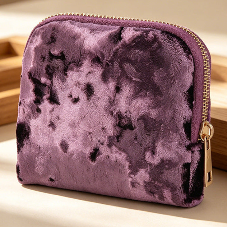 Purple velvet pouch with gold zipper on a wooden surface