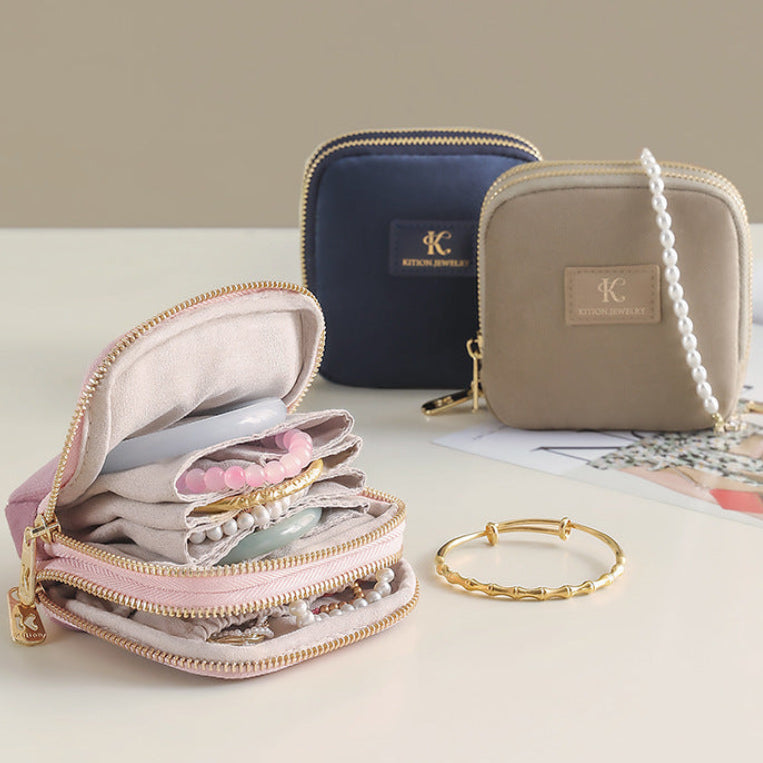 2-sided Jewelry organizer with jewelry items and a gold bracelet on a light surface.