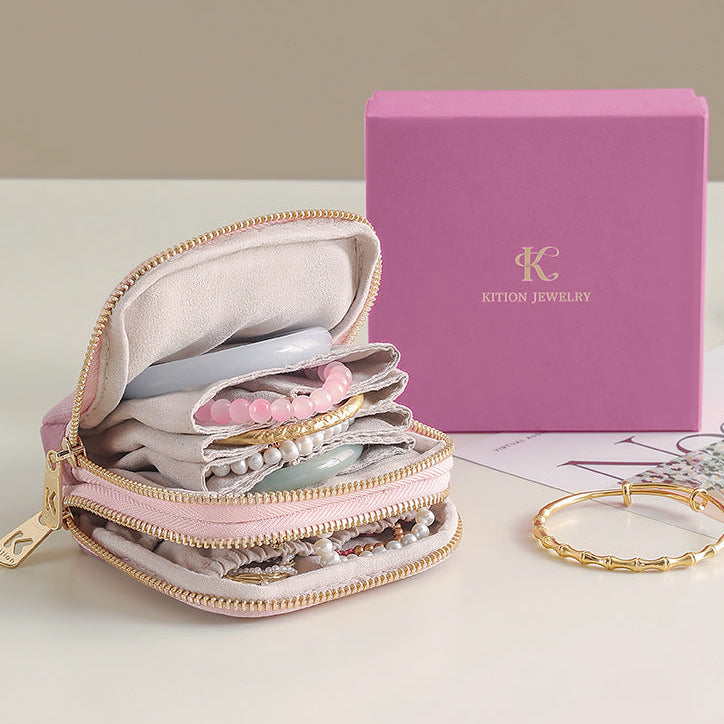 Pink jewelry case with jewelry items and a pink box on a light surface.