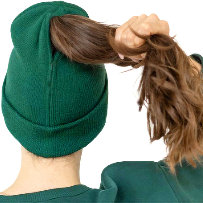 Green beanie being used to hold up a ponytail on a white background