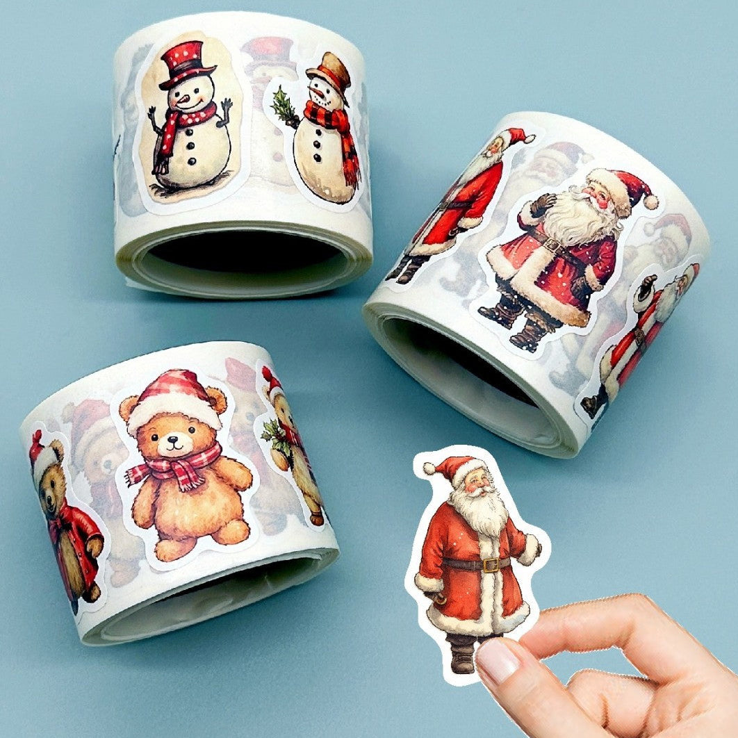 Three rolls of Christmas-themed stickers featuring Santa Claus, snowmen, and teddy bears on a light blue background.