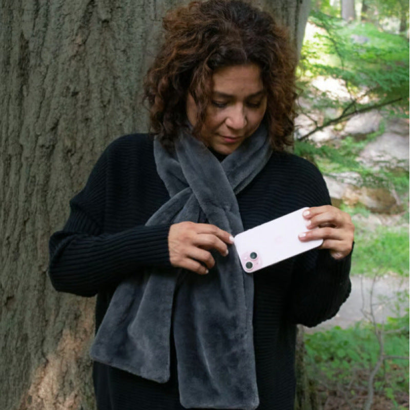 Woman putting her phone into her scarf pocket in a forest setting