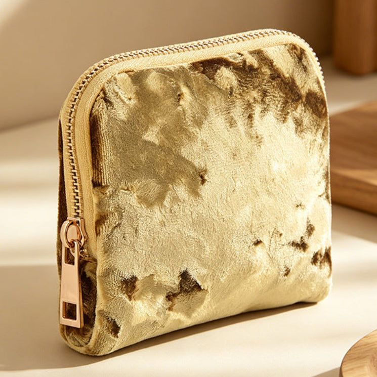 Gold textured pouch on a light surface with wooden items in the background