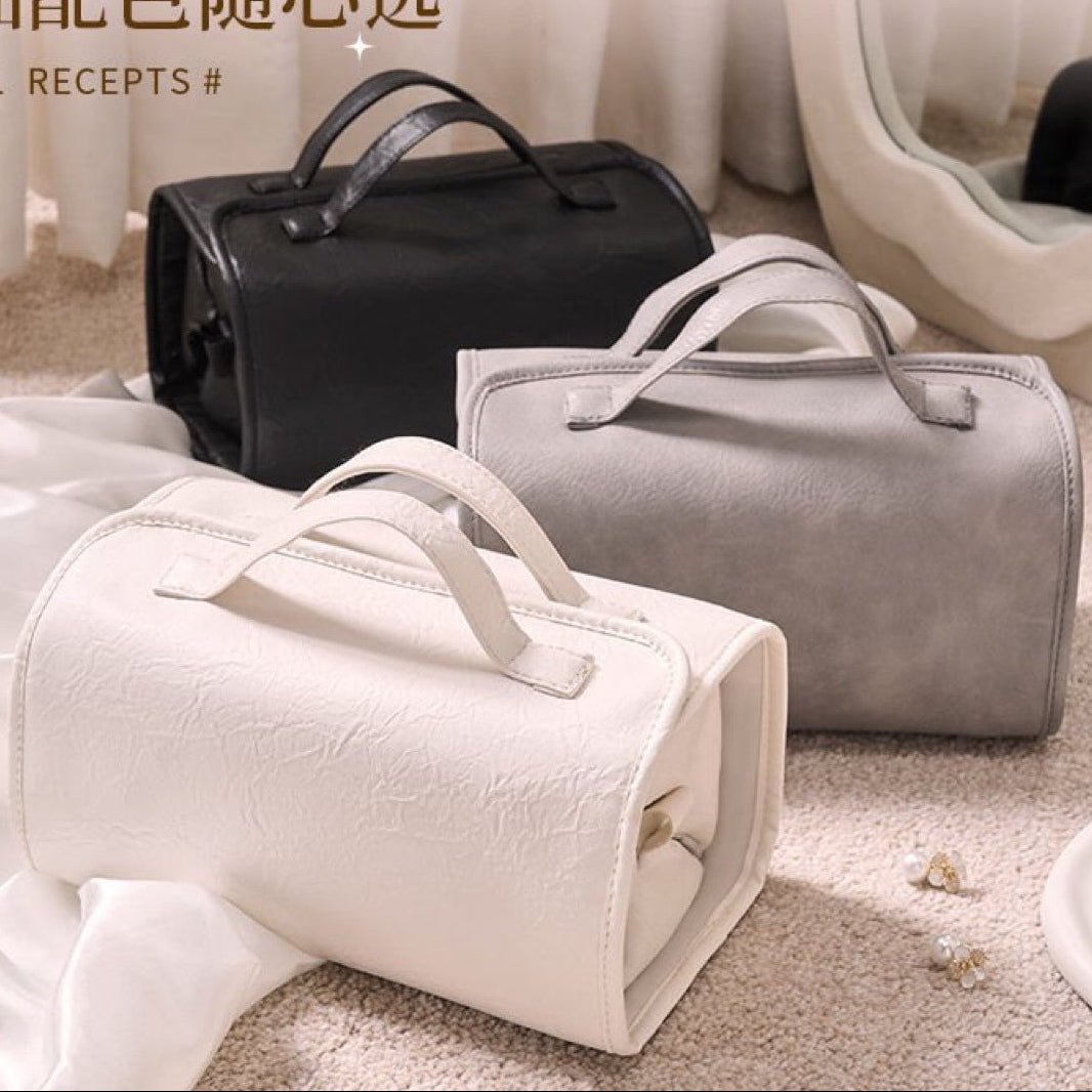 Three travel bags in black, white, and gray on a light background.